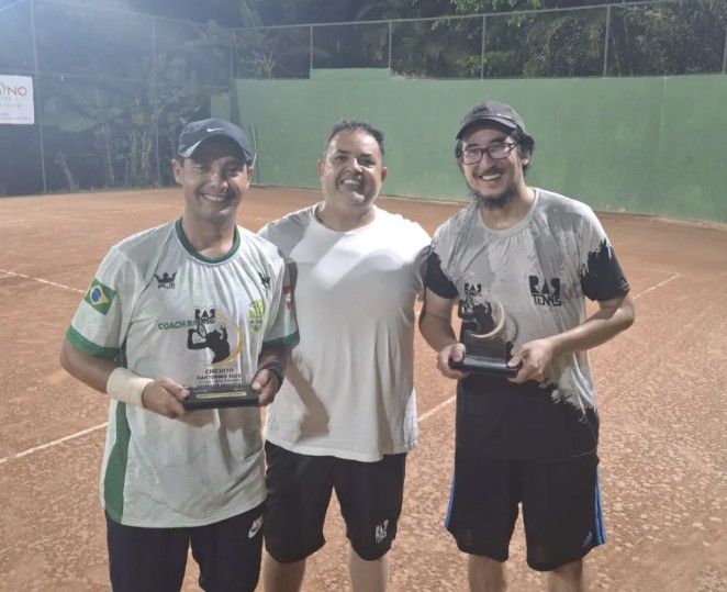 Rafael e dois alunos segurando troféus do Circuito RAR Tennis numa quadra de saibro